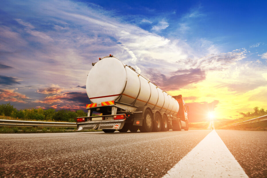 Rear view of big metal fuel tanker truck shipping fuel on the countryside road